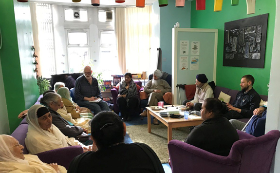 Group of people sitting in a room talking to each other 